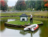 Public Services crew member performing duck house maintenance on an island in the middle of the pond